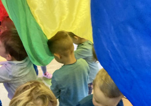 dzieci stoją pod kolorową chustą