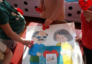 dzieci przyklejają serca na plakacie