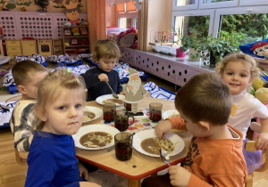 dzieci siedzą przy stolikach i jedzą świąteczny obiad