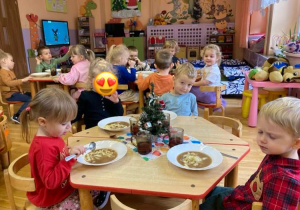 dzieci siedzą przy stolikach i jedzą świąteczny obiad