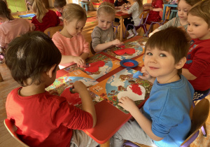 dzieci malują czerwoną farbą serca