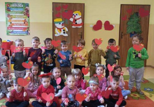 dzieci pozują do zdjęcia w dłoniach trzymają czerwone serduszka
