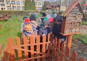 dzieci szukają oznak wiosny w ogrodzie przedszkolnym, sprawdzają czy w domku są już owady