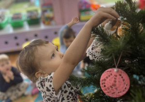 dzieci ubierają choinkę w sali przedszkolnej