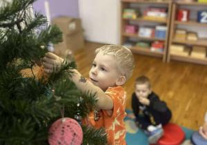 dzieci ubierają choinkę w sali przedszkolnej