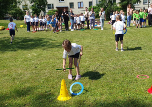 dzieci za pomocą laski gimnastycznej zbierają kolorowe krążki