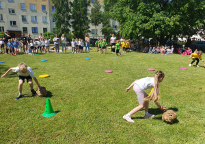 dzieci toczą kule do pachołka