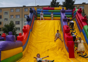 Dzieci z szerokimi uśmiechami skaczą na dmuchanym zamku.