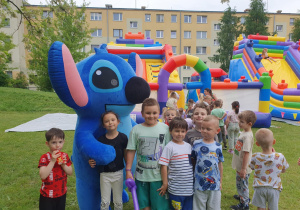 Duża maskotka Sticha otoczona przez roześmiane dzieci.