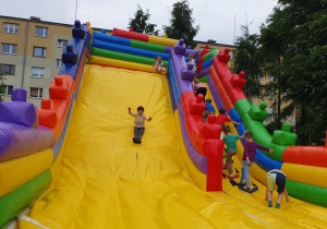 Dzieci z szerokimi uśmiechami skaczą na dmuchanym zamku.