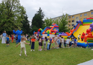 Radosna gromadka dzieci cierpliwie czeka w kolejce do dmuchanego zamku.