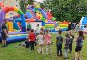 Radosna gromadka dzieci cierpliwie czeka w kolejce do dmuchanego zamku.