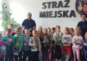 dzieci pozują do zdjęcia z pracownikami straży miejskiej