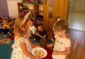 dziewczynka częstuje dzieci rogalikami