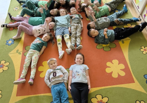 dzieci ułożyły na dywanie ze swoich sylwet drzewo