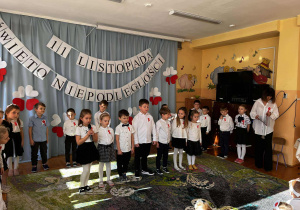 Recytacja patriotycznych wierszy – na zdjęciu widać grupę dzieci stojących w półkolu. Z przejęciem i zaangażowaniem mówią wiersze o wolności, ojczyźnie i bohaterstwie.