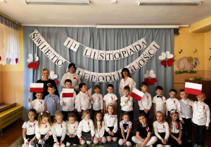 Nauczyciele z dziećmi – wspólne zdjęcie wychowawców z grupą przedszkolną. Wszyscy ubrani w odświętne barwy, dumni z pięknych występów swoich podopiecznych.