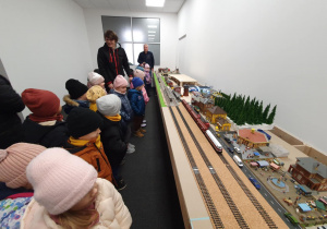 Model kolejki i pociągów ustawiony na osobnym stanowisku – dzieci z dużym zainteresowaniem przyglądają się wagonikom