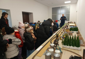Model kolejki i pociągów ustawiony na osobnym stanowisku – dzieci z dużym zainteresowaniem przyglądają się wagonikom