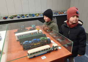 Dzieci pozują uśmiechnięte przy stole pełnym wyjątkowych modeli – pamiątkowe zdjęcie z wystawy.