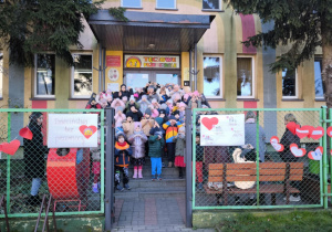 przeprzedszkolaki pozuja do zdjęcia przed budynkiem przedszkola