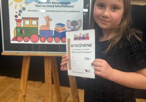 dziewczynka trzyma dyplom z wyróżnieniem