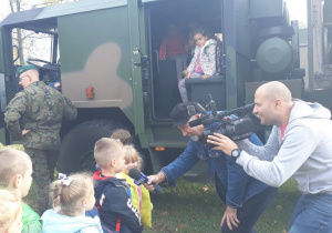 dzieci udzielają wywiadu reporterowi który trzyma w dłoniach mikrofon, z lewej strony stoi pan z kamerą
