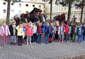 na zdjęciu przedszkolaki pozują do zdjęcia w tle widać dwa konie