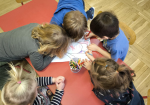 przedszkolaki siedzą przy stoliku, kolorują misia