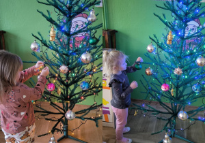 dzieci dekorują choinkę w sali przedszkolnej