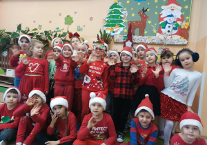 dzieci w czerwonych strojach pozuja do zdjęcia