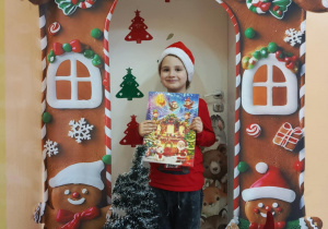 chłopiec pozuje do zdjecia w dłoniach trzyma kalendarz adwentowy