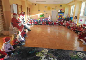 Fotografia przedstawia chwile, gdy Mikołaj i Pani Mikołajowa uczestniczą z dziećmi w śpiewaniu kolęd.