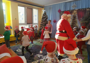 Fotografia przedstawia chwile, gdy Mikołaj uczestniczy z dziećmi w zabawach ruchowych