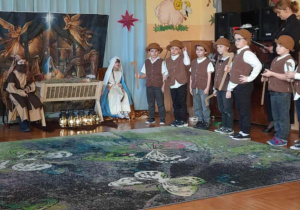 Przedszkolaki wcielające się w postacie Maryi, Józefa i aniołów przedstawiają scenę narodzin Jezusa w przygotowanej szopce.