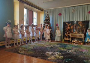 Na zdjęciu widać dzieci ubrane w stroje jasełkowe, które z dużym zaangażowaniem prezentują swoje role na scenie.