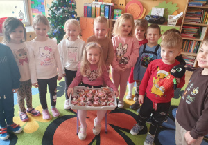 Na zdjęciu widać Michalinkę która siedzi w centrum grupy i z uśmiechem przyjmuje urodzinowe życzenia od koleżanek i kolegów.