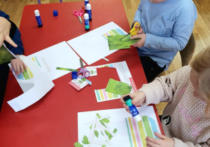 dzieci wykonują laurkę, wycinają nożyczkami, naklejają na kartkę papieru