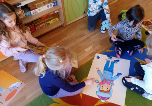 dzieci ubierają lalkę