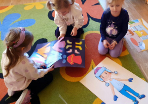 dzieci ubierają lalkę