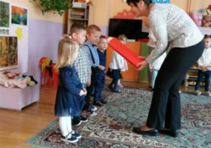 Pani dyrektor czerwoną kredką poacuje dzieci na przedszkolaków "Tęczowego Przedszkola"