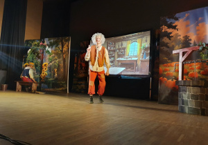 Na zdjęciu widoczna jest scena z przedstawienia teatralnego „Pinokio”. Na scenie znajduje się dekoracja sceniczna oraz postać krasnala będąca elementem spektaklu.