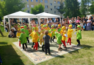 Na zdjęciu widoczne są dzieci występujące na scenie podczas festynu rodzinnego. Przedszkolaki tańczą w rytm muzyki, prezentując przygotowany układ choreograficzny przed zgromadzoną publicznością.