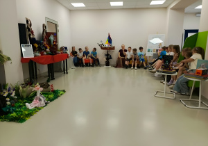 Dzieci zgromadzone w bibliotece uczestniczą w zajęciach edukacyjnych prowadzonych przez autorkę książek dla dzieci. Spotkanie ma formę rozmowy i wspólnej zabawy z wykorzystaniem rekwizytów nawiązujących do treści książek.