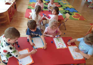 Na zdjęciu przedszkolaki przygotowują prace z okazji Dnia Mamy. Dzieci z zainteresowaniem ozdabiają swoje portrety, rozwijając kreatywność i sprawność manualną.