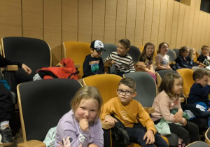 Na zdjęciu dzieci siedzą na widowni Centrum Integracji Ratusz i oglądają przedstawienie teatralne. Przedszkolaki skupiają uwagę na wydarzeniach rozgrywających się na scenie.
