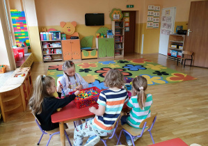 Przedszkolaki wspólnie spędzają poranny czas przy stolikach, podejmując rozmowy i wybierając zabawy.