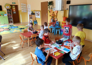 Dzieci wykonują pracę plastyczną przedstawiającą ich przedszkole.