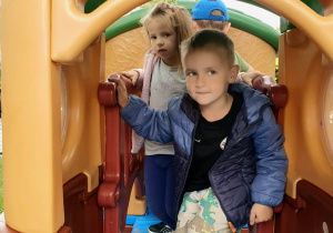Dzieci korzystają z urządzenia rekreacyjnego w przedszkolnym ogrodzie podczas zabawy na świeżym powietrzu.