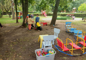 Dzieci planują wspólną zabawę w ogrodzie, rozmawiając i wybierając miejsce oraz potrzebne zabawki.